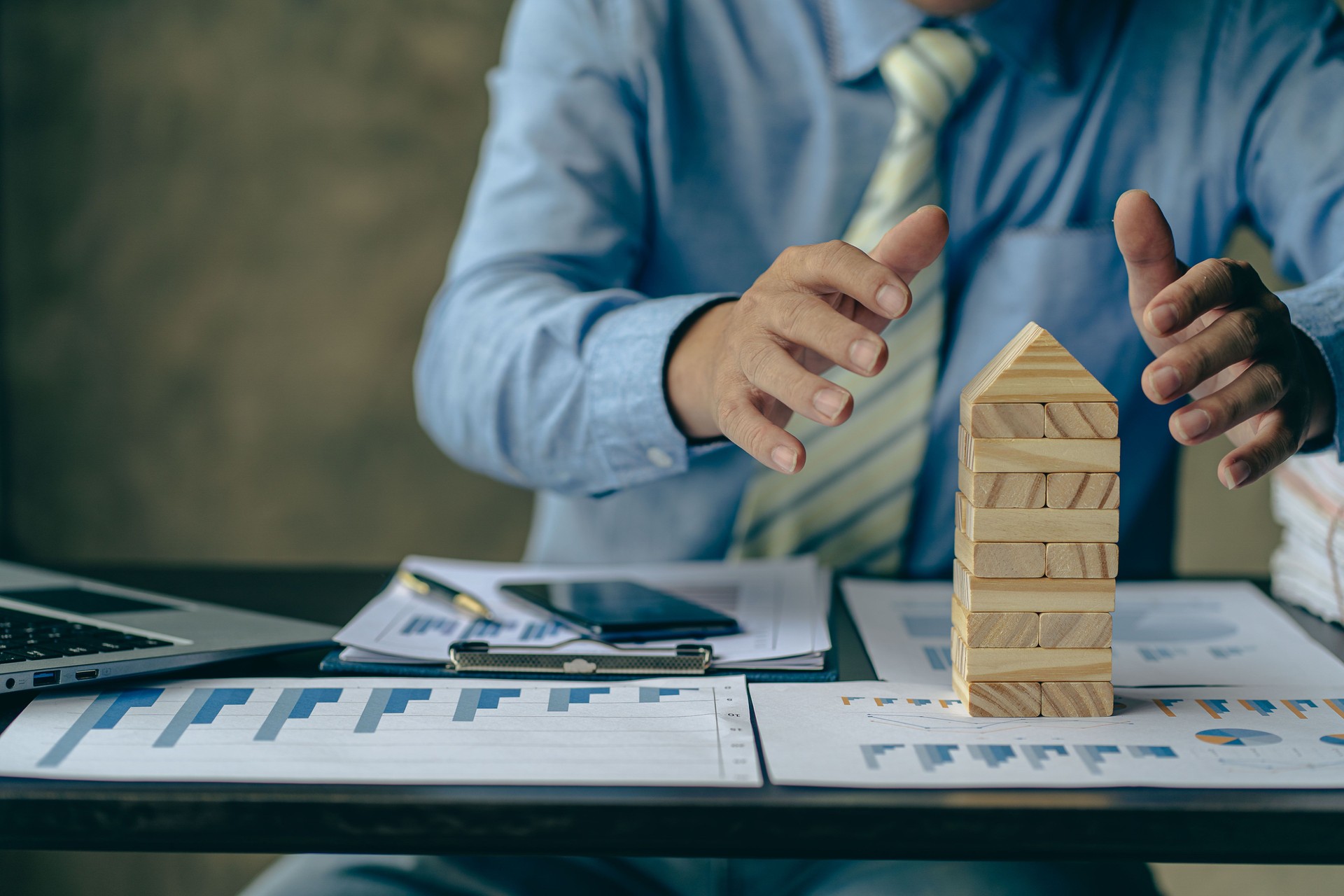 Businessman working with showing business graph Business expansion and growth plan With wooden block tower next to it with direction of growth and success, property and real estate insurance concept